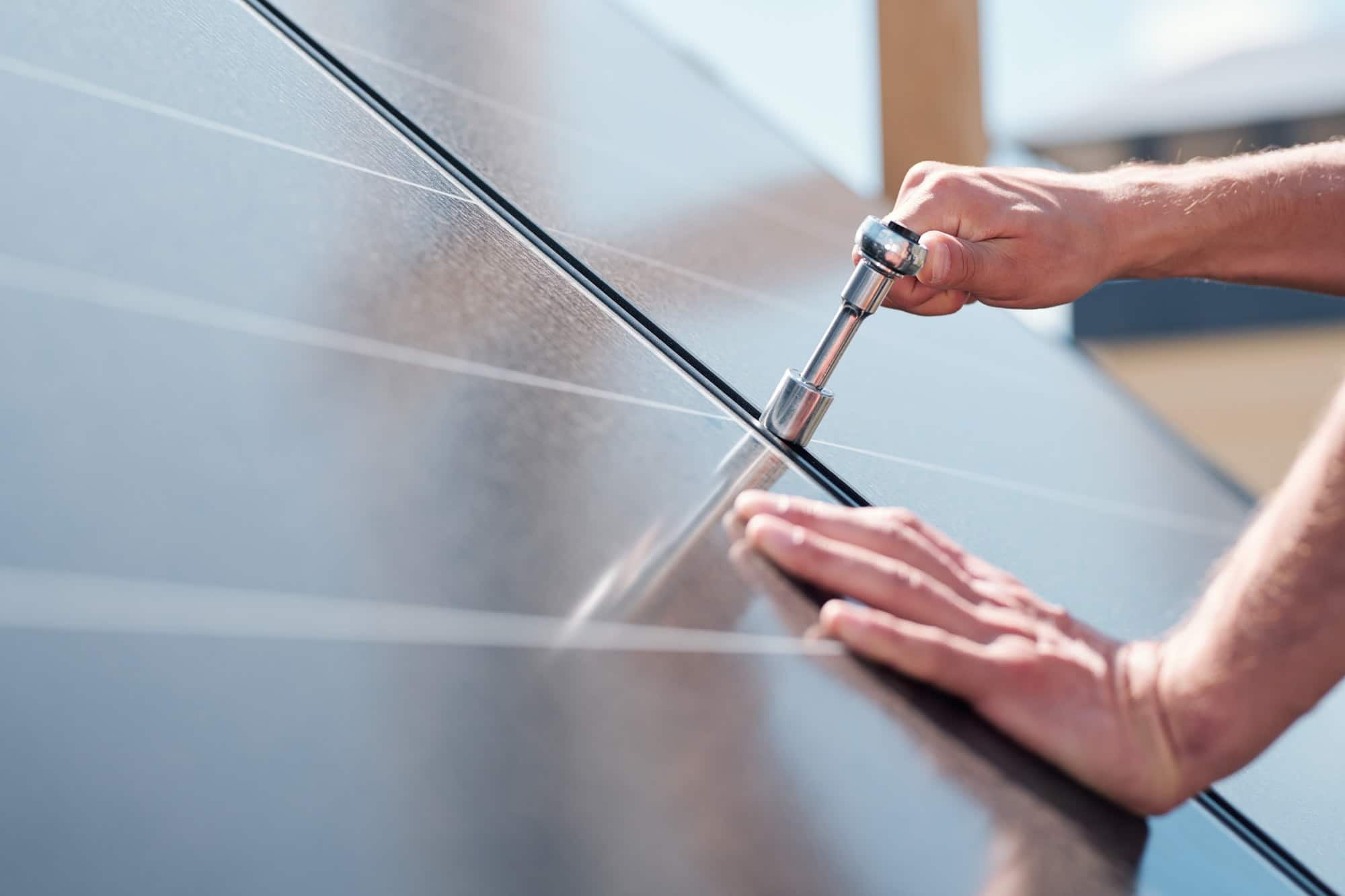 Hands of contemporary master with screw adjusting or installing solar panels