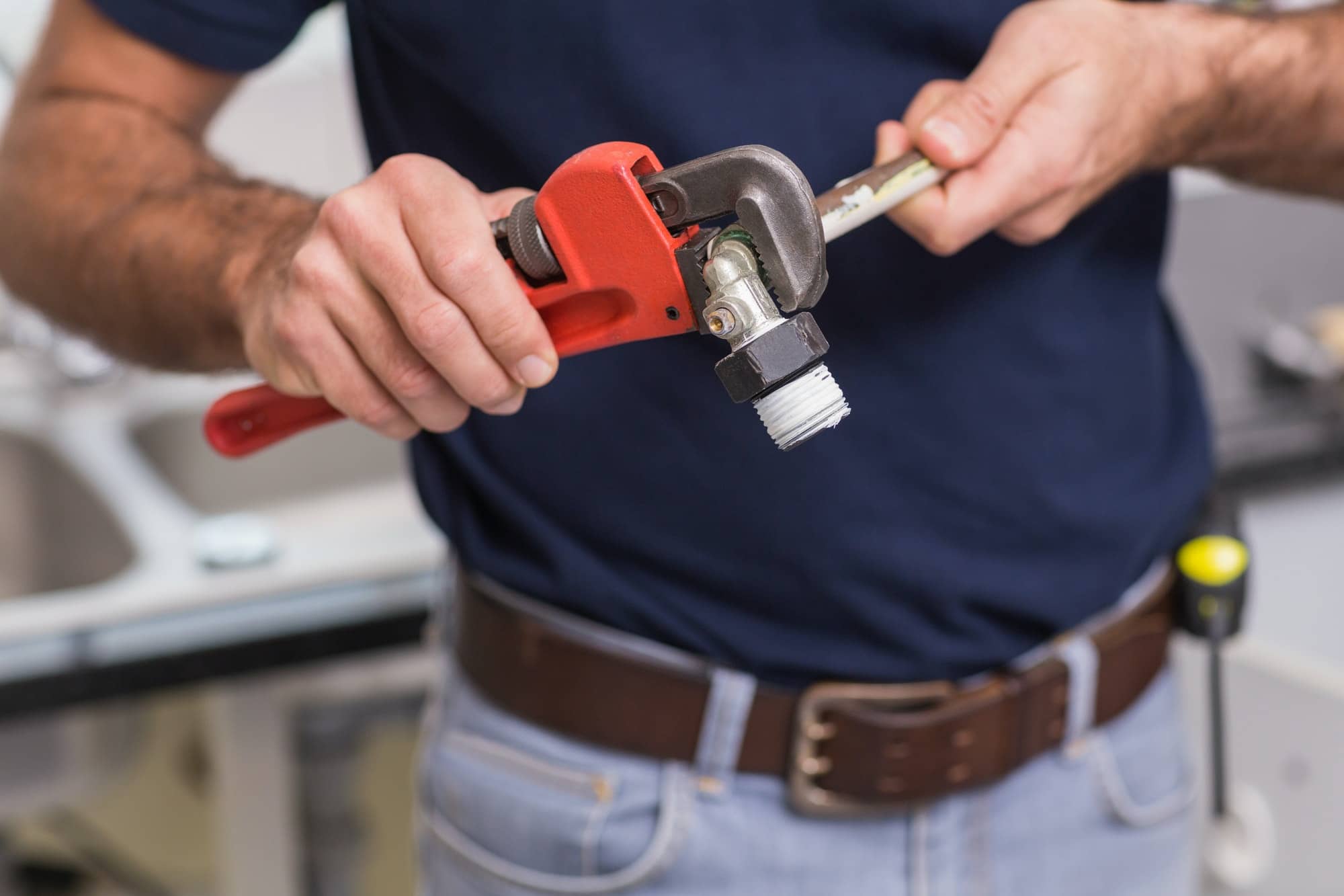 Plumber fixing pipe with wrench in the kitchen