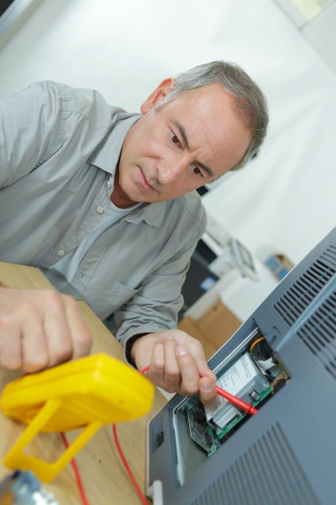 Senior technician using multi meter to test electrical appliance