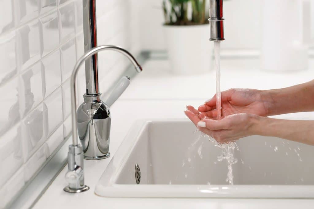 Woman washing and cleaning her hands under flowing tap water