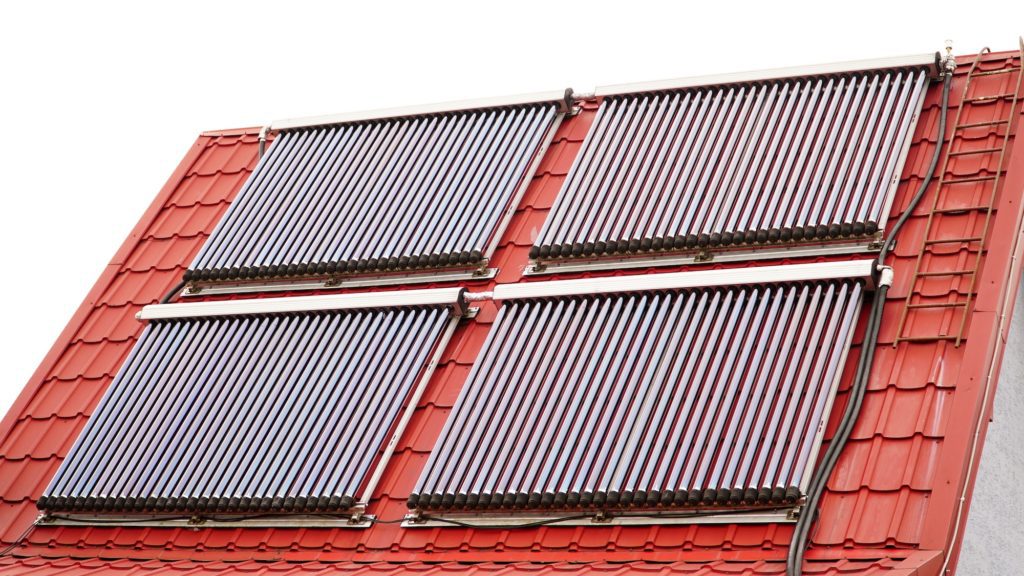 Solar glass tube hot water panel array mounted on a tiled roof. water heating batteries.
